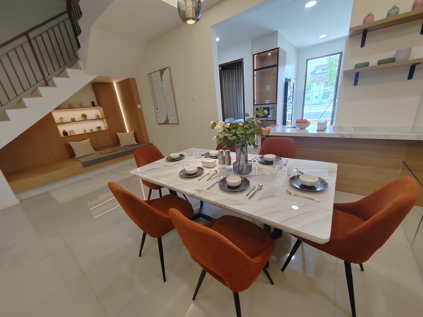 Foto ruang makan rumah contoh Adenia dengan meja enam kerusi, ruang bawah tangga dan dapur di belakang