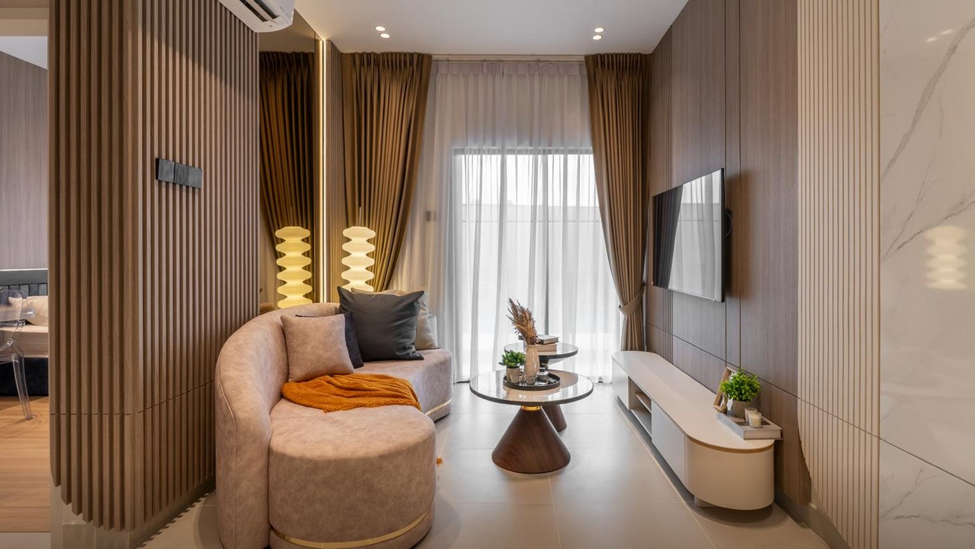Ara Residences — Puchong — Foto show unit Ara Residences Jenis A: ruang tamu dengan sofa lengkung, meja kopi, kabinet TV dan pintu gelangsar ke balkoni