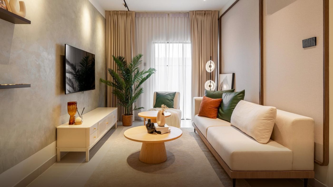 Foto show unit Ara Residences Jenis B: ruang tamu dengan sofa krim, meja kopi bulat dan TV di dinding