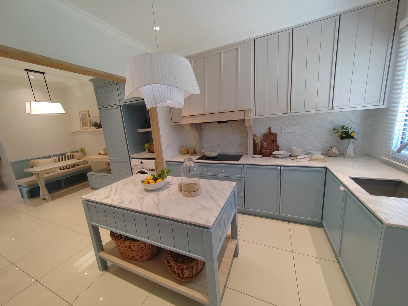 Foto show unit Aulica: dapur dengan kabinet biru muda, pulau dapur berpermukaan marmar dan mesin basuh