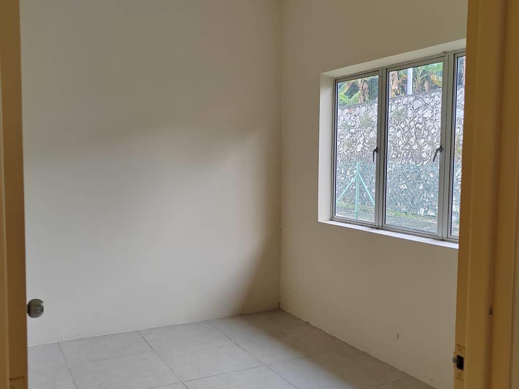 Foto sebenar sebuah bilik di bahagian belakang rumah teres dengan tingkap menghadap tembok penahan batu