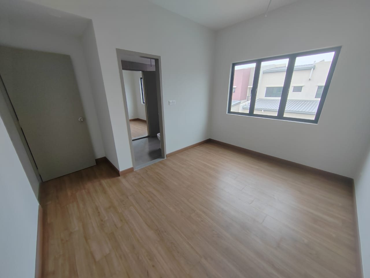 Foto sebenar bilik tidur unit atas Elegan Residensi yang kosong dengan lantai berkemasan kayu, tingkap dan pintu bilik air