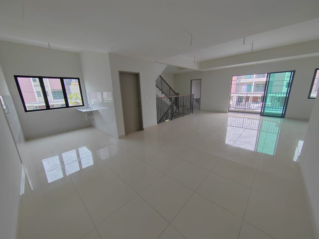 Foto sebenar ruang tamu, ruang makan dan dapur terbuka unit atas Elegan Residensi yang kosong dengan tangga dan pintu ke balkoni
