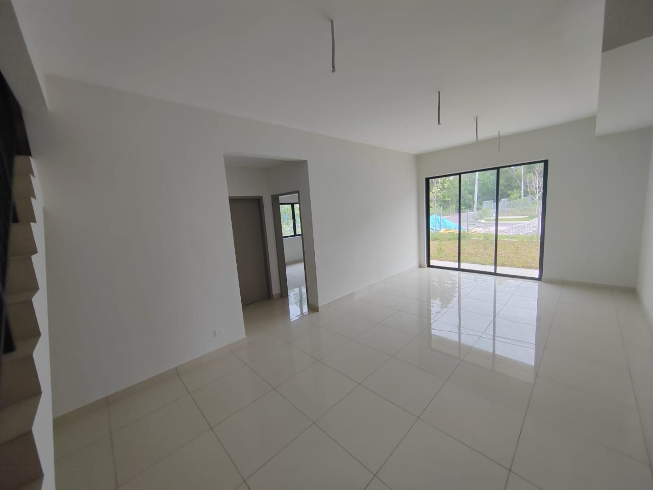Foto sebenar ruang tamu dan ruang makan unit bawah Elegan Residensi yang kosong dengan lantai jubin dan pintu kaca gelangsar ke laman