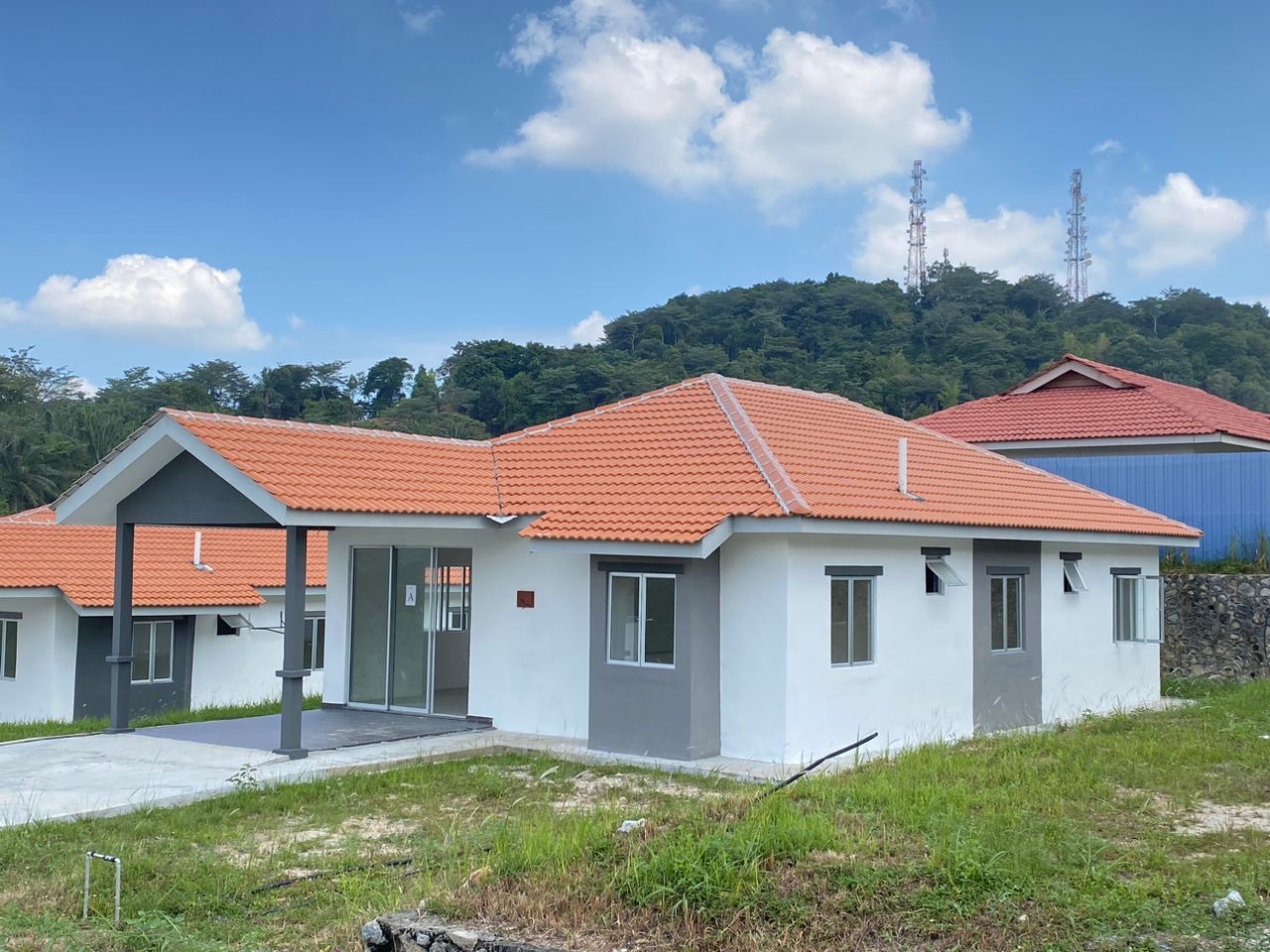 Foto sebenar rumah contoh Kerayong Hills Jenis A (Mawar): banglo setingkat putih dengan bumbung genting jingga dan laman berumput