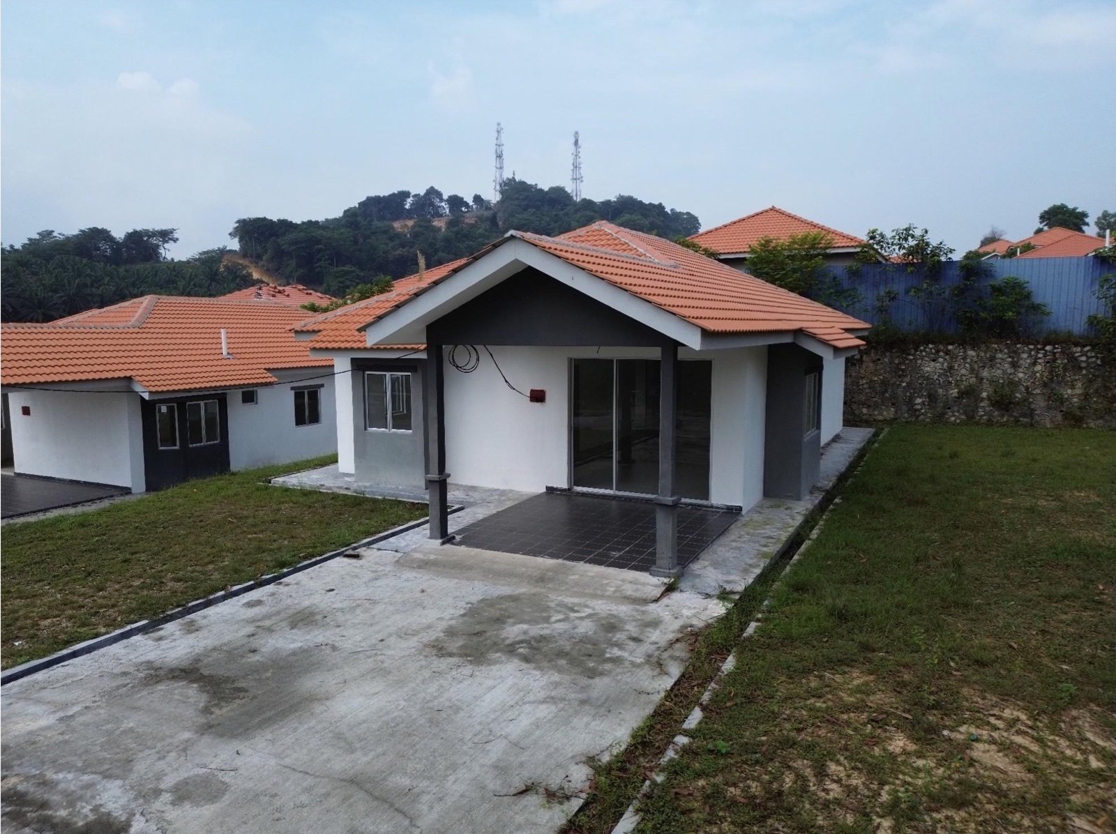 Foto sebenar rumah contoh banglo setingkat selepas siap dibina, dengan laman berumput dan anjung kereta