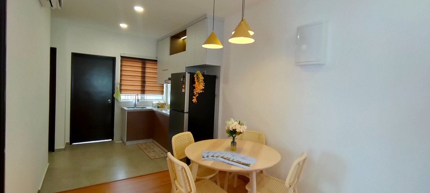 Foto ruang makan unit contoh bawah dengan meja bulat, kerusi dan lampu gantung