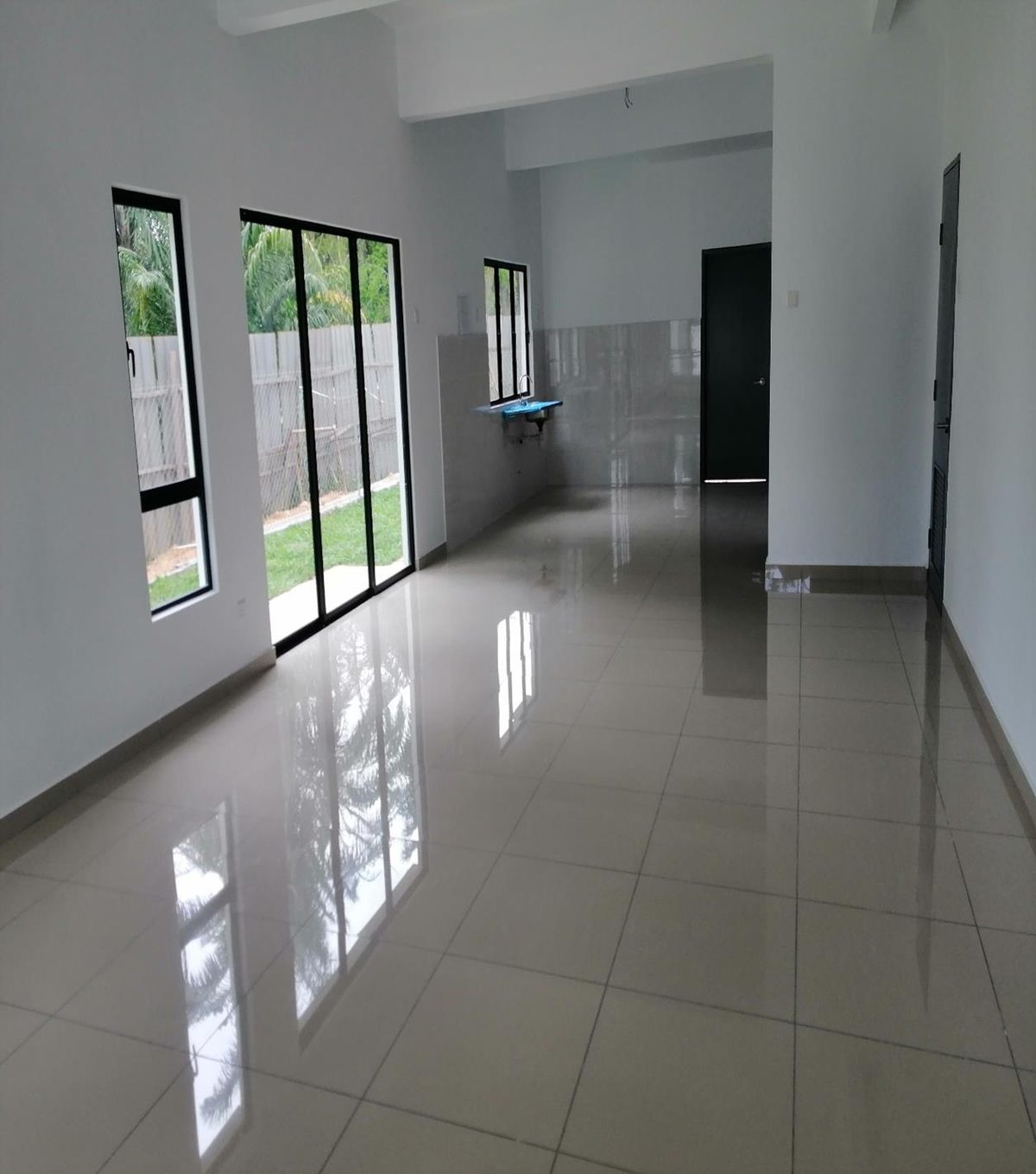 Foto sebenar ruang dalam rumah contoh Taman Semarang Intan fasa terdahulu: ruang lapang berjubin dengan pintu gelangsar kaca ke laman belakang dan sinki di kawasan basah