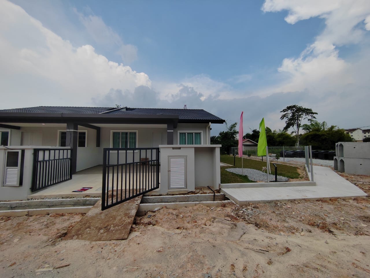 Foto sebenar bahagian hadapan rumah contoh Semi-D dengan pagar dan laluan masuk