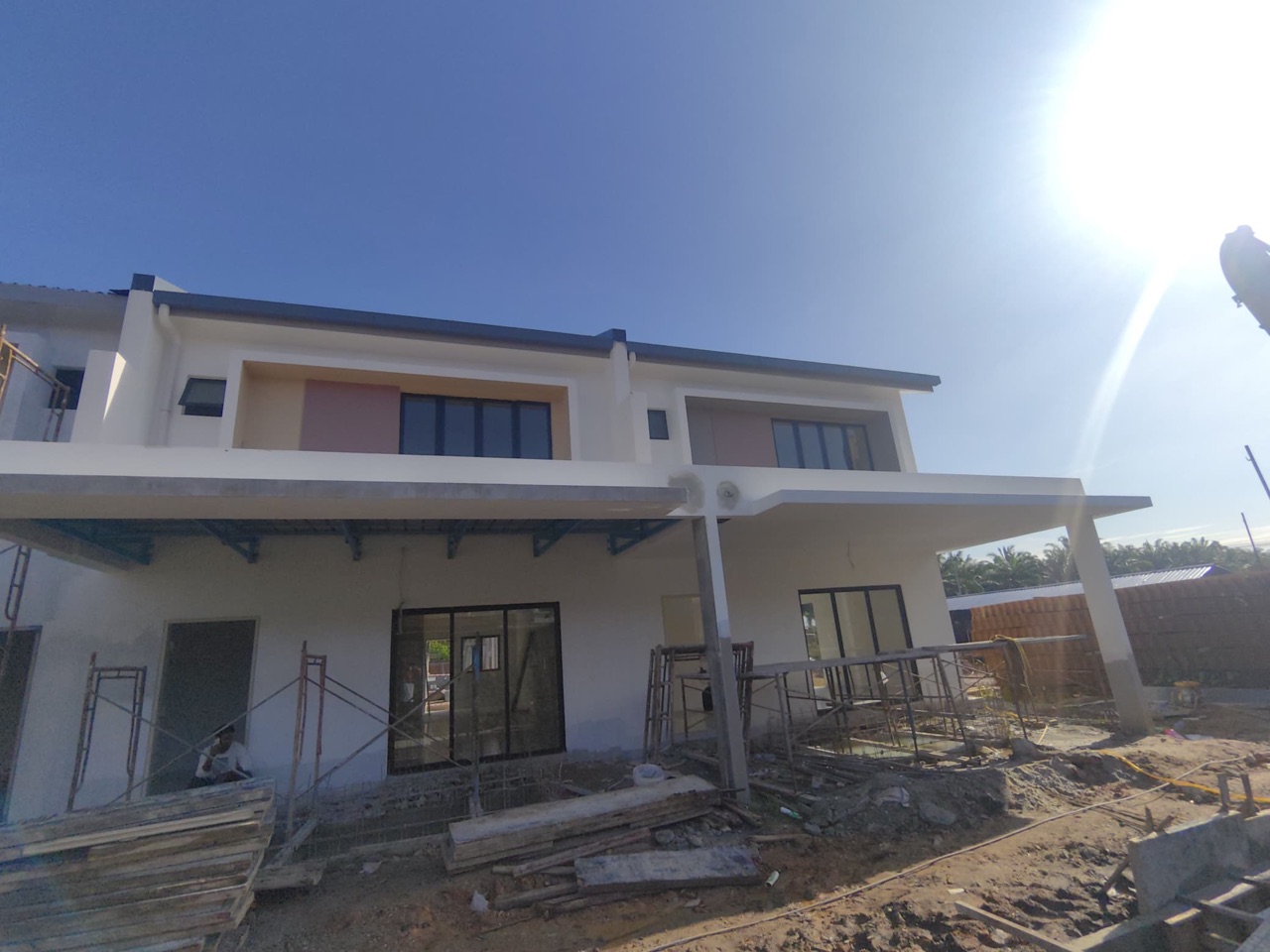 Foto sebenar bahagian hadapan rumah teres dua tingkat di tapak projek dengan anjung kereta