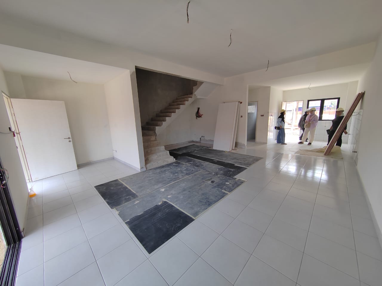 Foto sebenar ruang tamu dan ruang makan berlantai jubin putih dengan tangga ke tingkat atas